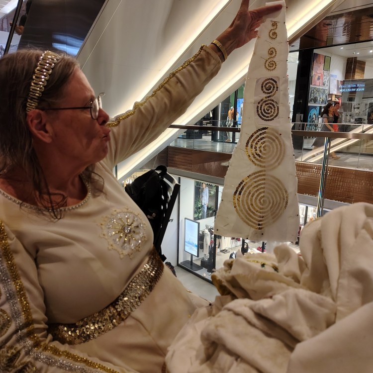 Suzanne Muldowney adding godet to a costume she is sewing in a mall at Hudson Yards NYC